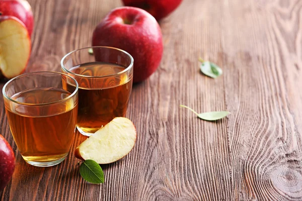 Copos de suco de maçã e frutas na mesa de perto — Fotografia de Stock