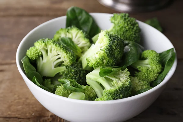 Broccoli freschi con spinaci in ciotola sul tavolo di legno da vicino — Foto Stock