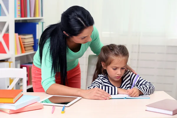 Schulmädchen macht Hausaufgaben mit Mutter — Stockfoto
