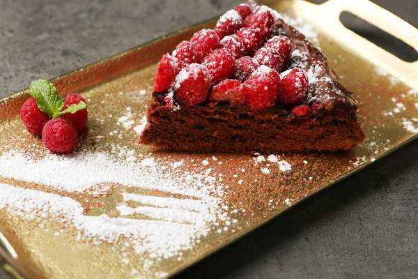 Kuchenstück mit Schokoglasur und Himbeeren auf Blech, Nahaufnahme — Stockfoto