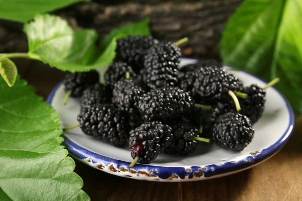 Moras maduras con hojas verdes en la mesa de cerca —  Fotos de Stock