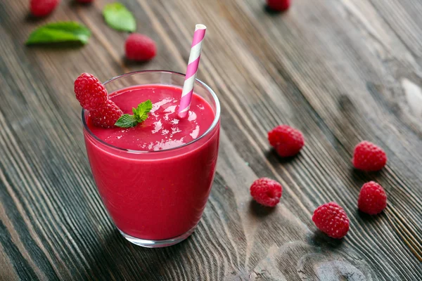 Glass of raspberry milk shake with berries on wooden table close up — Stock Photo, Image