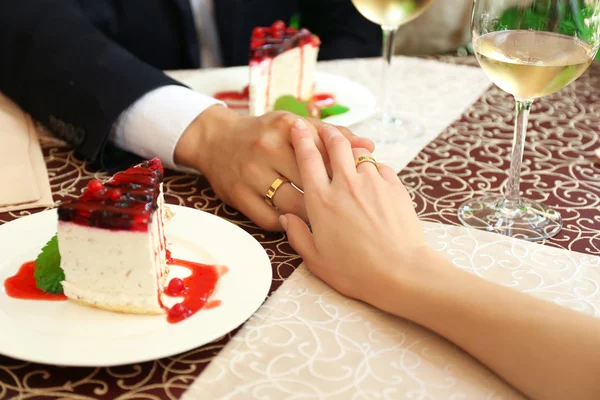 Handen van pasgetrouwden aan tafel in café — Stockfoto