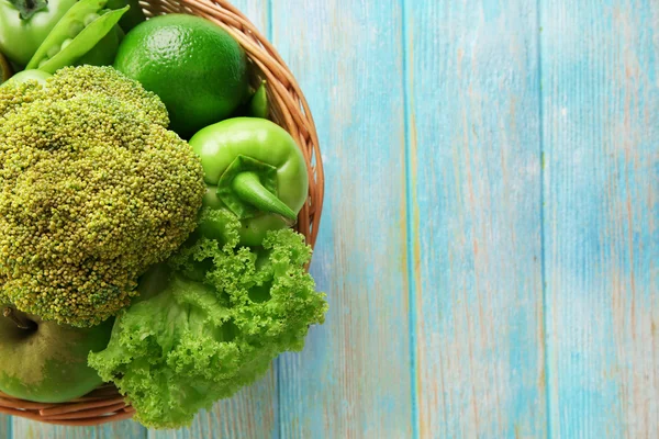 Verse groene voeding in rieten mand op houten achtergrond — Stockfoto