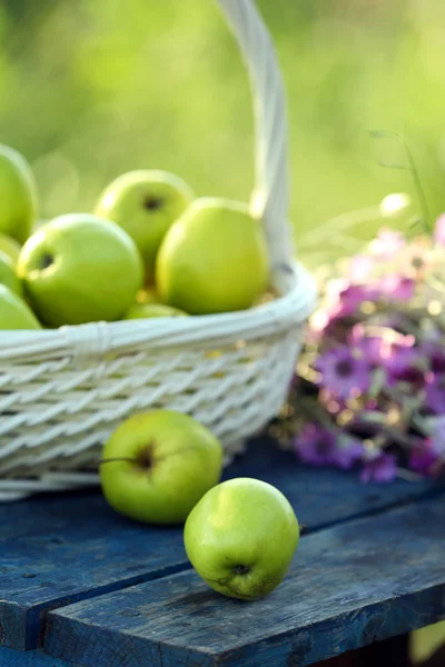 Grüne Äpfel mit Strauß Wildblumen auf Holztisch, Nahaufnahme — Stockfoto
