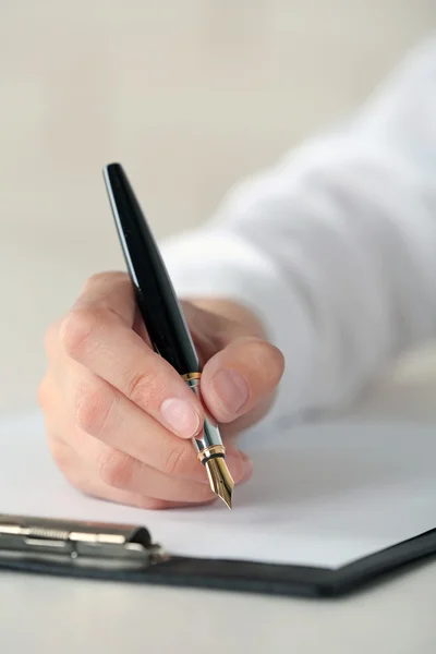 Hand mit Federschrift auf Papier Stockbild