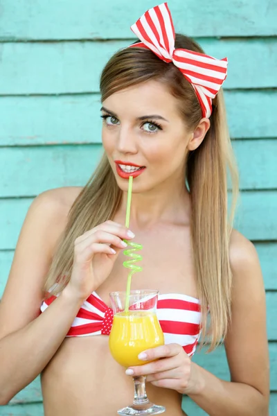 Красива дівчина з красивою посмішкою з коктейлем на кольоровому дерев'яному фоні — стокове фото