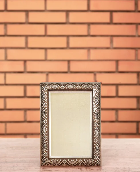 Alter leerer Rahmen steht auf Tisch auf Backsteinwand Hintergrund — Stockfoto