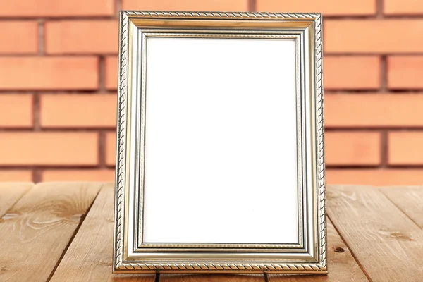 Old empty frame standing on table on brick wall background