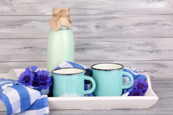 Sticle și cești de lapte cu flori de porumb pe tava de lemn — Fotografie, imagine de stoc