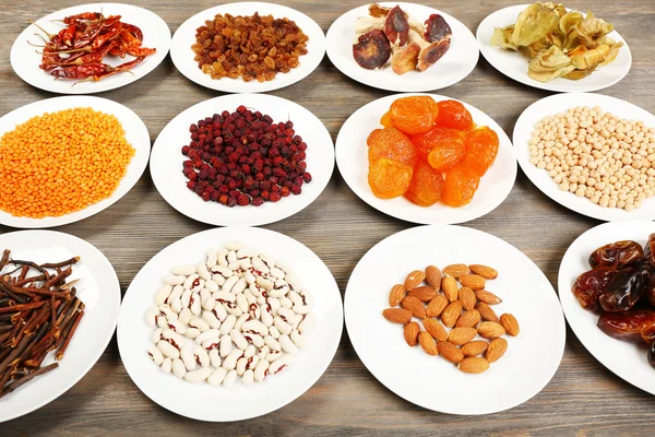 Different products on saucers on wooden table, closeup — Stock Photo, Image