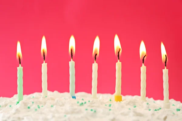 色の背景にろうそく付きの誕生日ケーキ — ストック写真