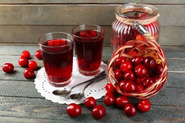 Glasses of sweet homemade cherry compote on table on wooden background clipart