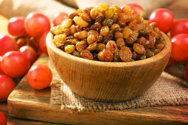 Raisins in bowl with grapes on table close up — Stock Photo, Image