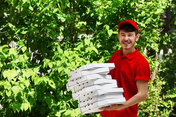 Rapaz de entrega com caixa de pizza de papelão, ao ar livre — Fotografia de Stock