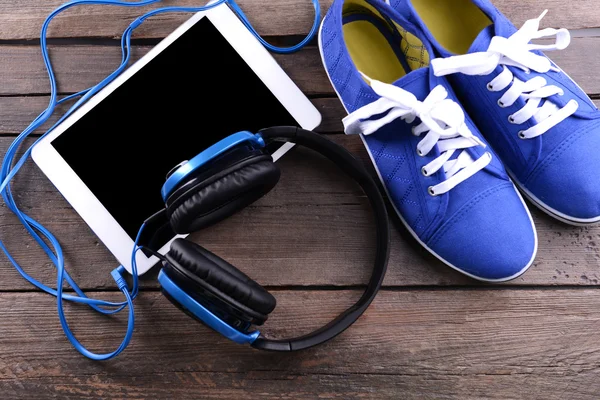 Spor ayakkabı ve tablet ahşap arka plan üzerinde kulaklık — Stok fotoğraf