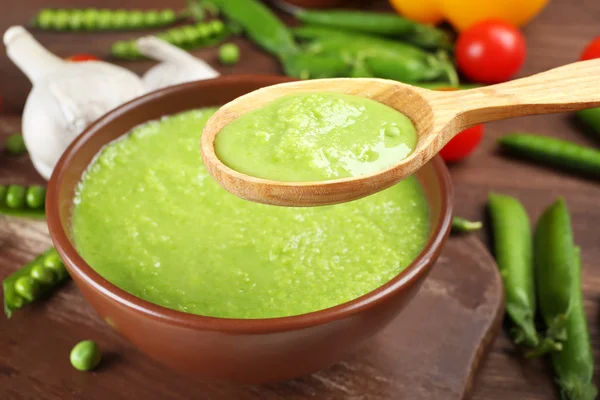 Tasty peas soup and vegetables on table close up — Stock Photo, Image