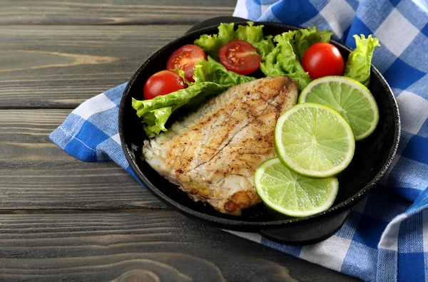 Plat de filet de poisson avec salade et citron vert sur la table close up — Photo