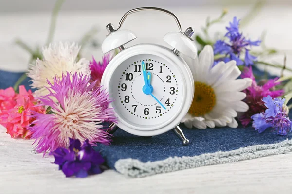Μικρό Ξυπνητήρι με όμορφα λουλούδια στο τραπέζι σε κοντινό πλάνο — Φωτογραφία Αρχείου
