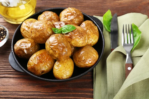 Patatas al horno en sartén sobre mesa de madera, primer plano —  Fotos de Stock