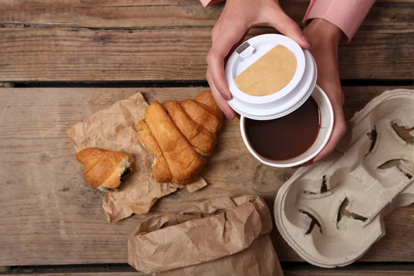 Las manos femeninas sosteniendo la taza de café y galletas en la mesa de madera de cerca — Foto de Stock