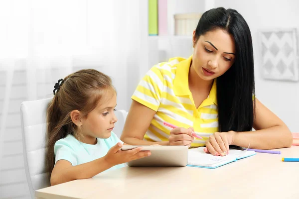 Beautiful school girl doing homework with mother at home — Stock Photo, Image