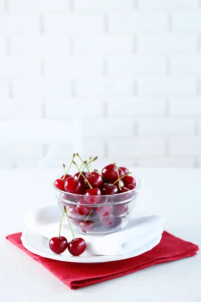 Třešně a višně ve skleněné mísy na stole, na světlé pozadí — Stock fotografie