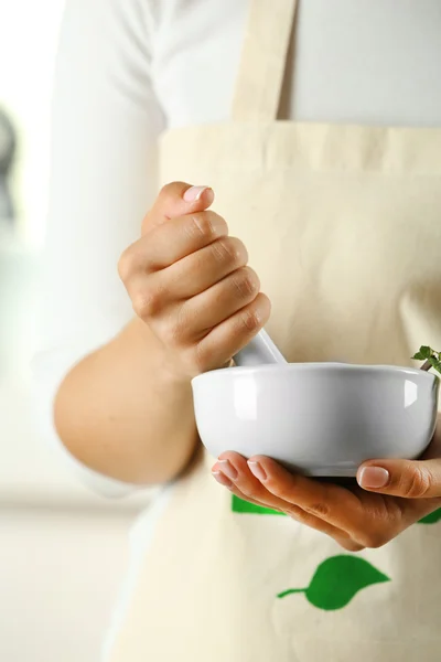 Frauenhände mit Mörser mit Kräutern auf hellem Hintergrund — Stockfoto