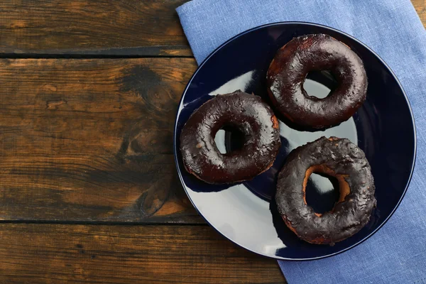 Delicious doughnuts with chocolate icing on table close up — Stock Photo, Image