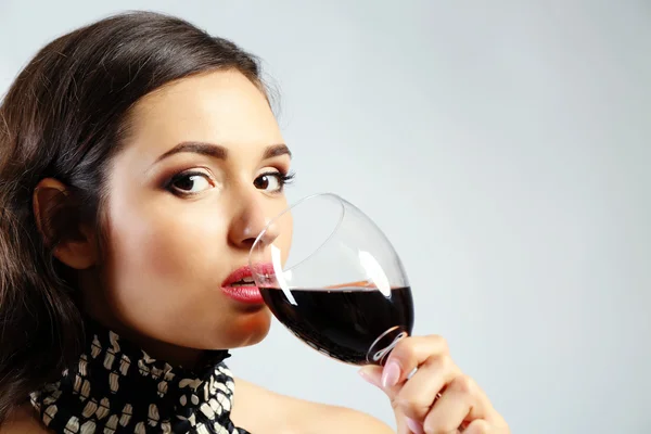 Retrato de jovem com copo de vinho tinto sobre fundo cinza — Fotografia de Stock