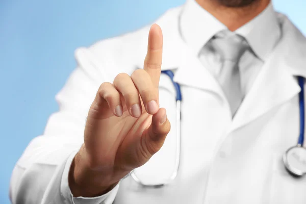 Doctor pointing his finger up on blue background — Stock Photo, Image