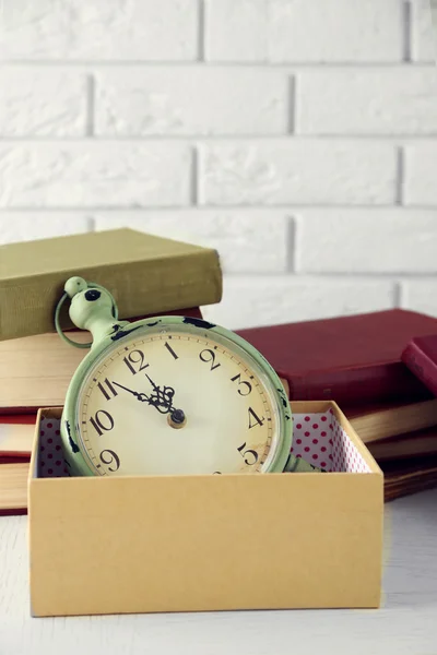 Clock and vintage books, on light wall background — Stock Photo, Image