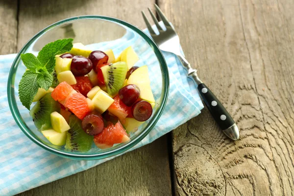 Salade de fruits dans un bol en verre, sur fond en bois — Photo