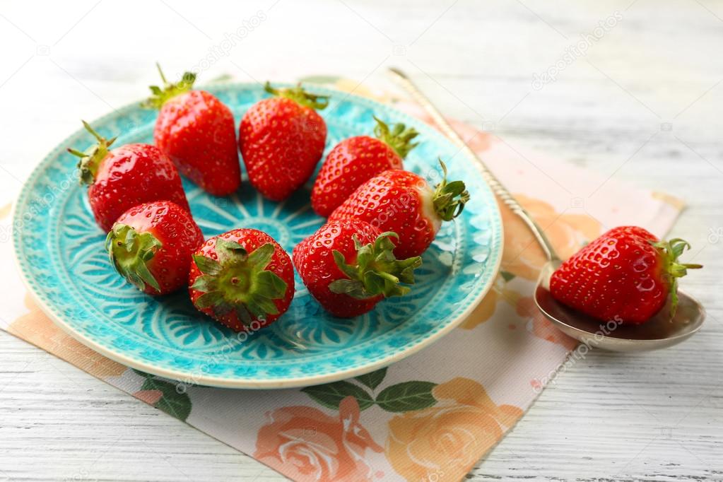 Strawberries on color plate, on color wooden background