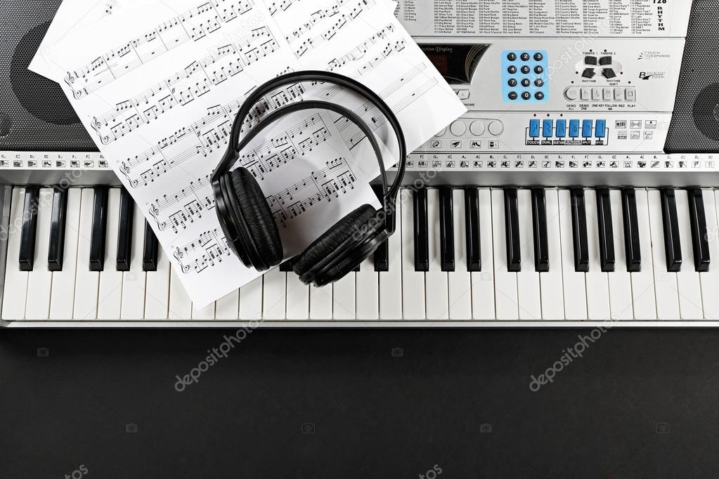 Headphones with music notes on synthesizer close up