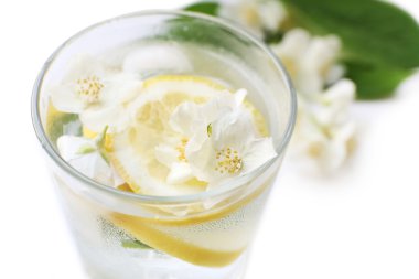 Bardak soğuk ferahlatıcı yaz içeceği çiçekli ve masada limon dilimleri kapat