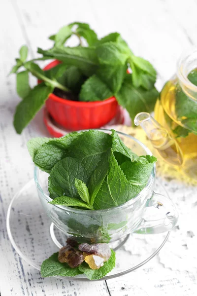 Foglie di menta in tazza di vetro su sfondo di legno di colore — Foto Stock