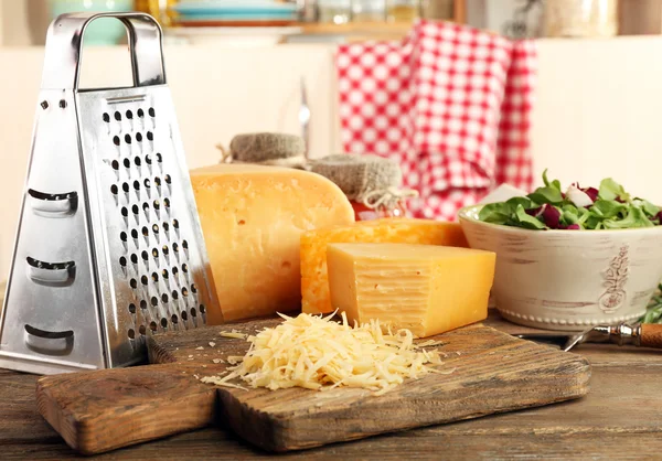 Queso rallado sobre mesa de madera sobre tabla de cortar en cocina —  Fotos de Stock