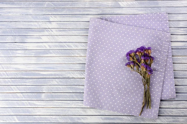 Hermosas flores secas en servilleta sobre fondo de madera — Foto de Stock