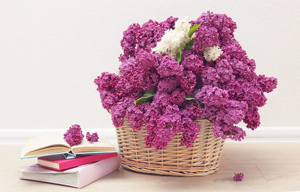 Beautiful lilac flowers in basket on floor in room close-up — Stock Photo, Image