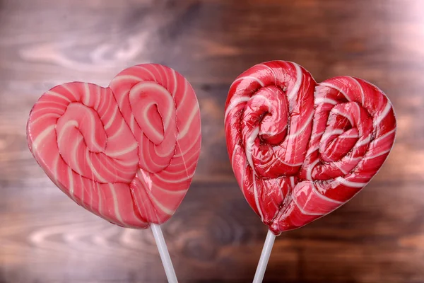 लकड़ी की पृष्ठभूमि पर दिल के आकार में उज्ज्वल lollipops — स्टॉक फ़ोटो, इमेज