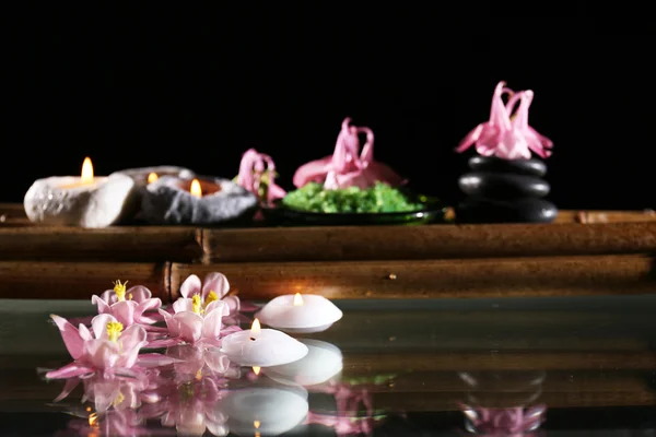 Hermosa composición de spa con flores y velas sobre fondo negro — Foto de Stock