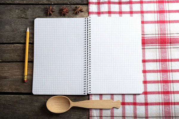 Livro de receitas aberto e especiarias em guardanapo, em fundo de madeira — Fotografia de Stock