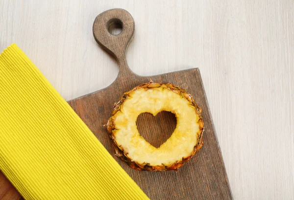 Pineapple slice with cut in shape of heart on wooden background — Stock Photo, Image