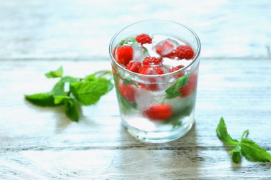 Bir bardak soğuk, ferahlatıcı yaz içeceği. Masada böğürtlen ve buz var.