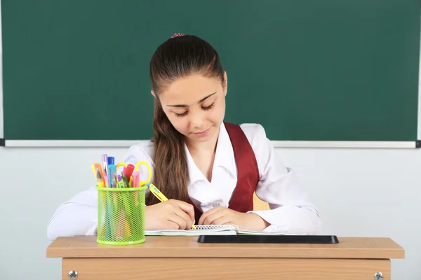 Beautiful little schoolgirl in classroom near blackboard — Stock Photo, Image