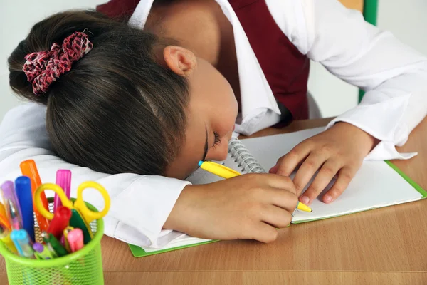 Schöne kleine Schulmädchen schlafen auf Schreibtisch — Stockfoto