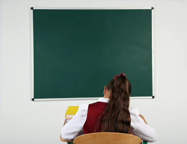 Vacker liten skolflicka i klassrummet nära blackboard — Stockfoto