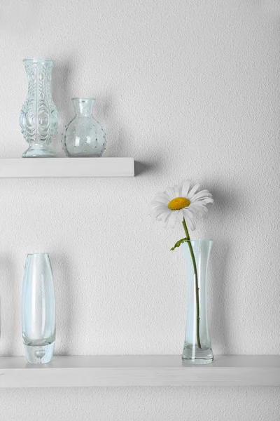 Dekorativa glas vaser med blomma på trähylla på vit tapet bakgrund — Stockfoto