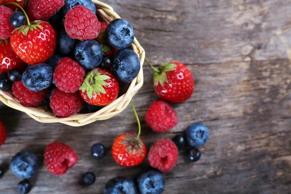 Zoete smakelijke bessen in mand op houten tafel close-up — Stockfoto